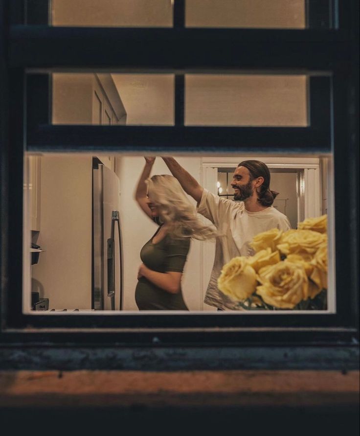 a man and woman standing in front of a window