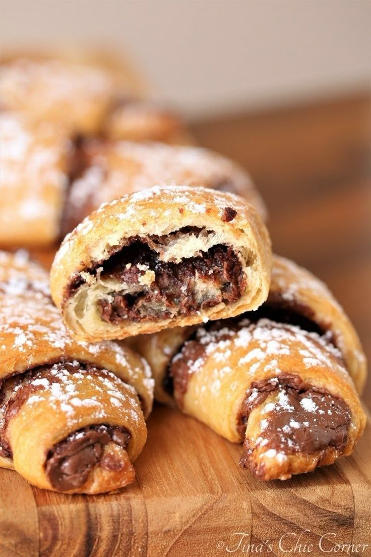 chocolate filled pastries stacked on top of each other with powdered sugar in the middle