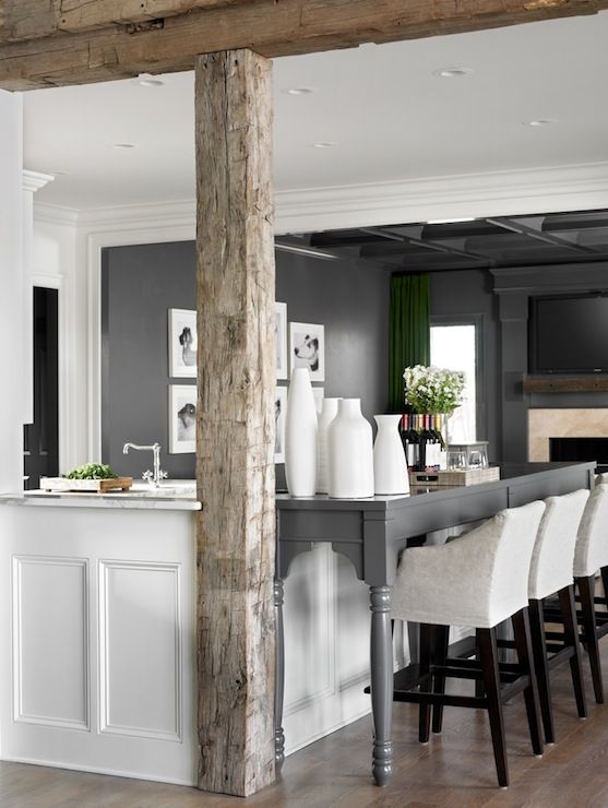 a dining room table with chairs and vases on top of it in front of a kitchen island