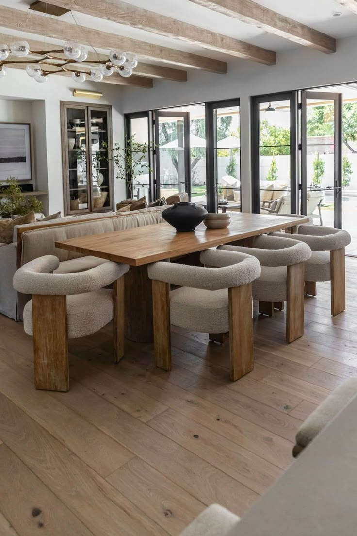 a large wooden table sitting inside of a living room next to a window filled with lots of windows