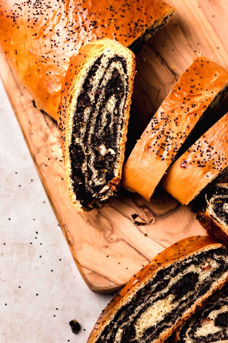 sliced black and white swirly bread on a cutting board with poppy seed sprinkles