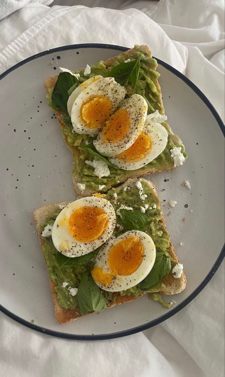 two slices of toast topped with eggs and spinach