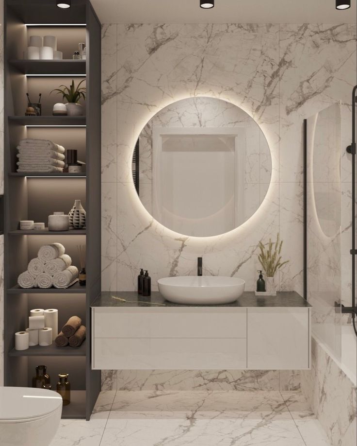 a bathroom with marble walls and flooring is shown in this image, there is a round mirror on the wall above the sink