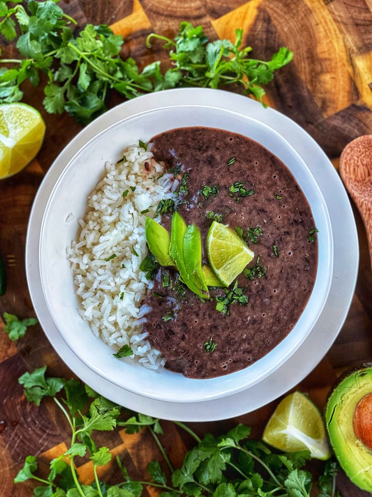 a white bowl filled with black beans, rice and avocado on top of a wooden table