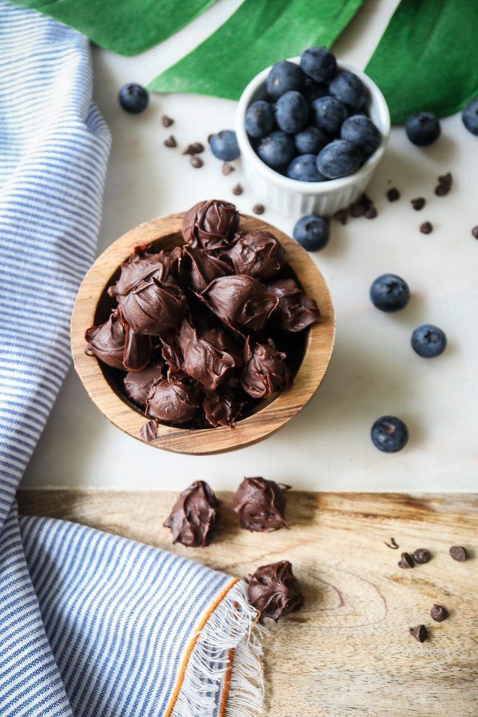 a wooden bowl filled with chocolate covered blueberries