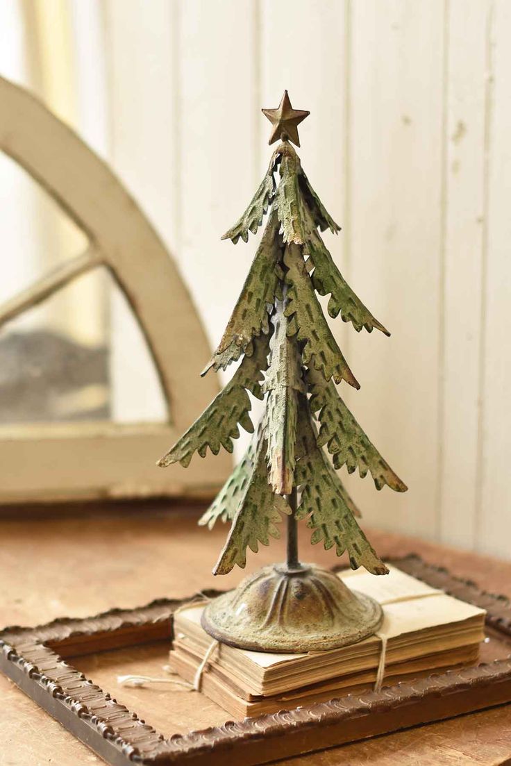 a small wooden christmas tree sitting on top of a table next to a book and mirror