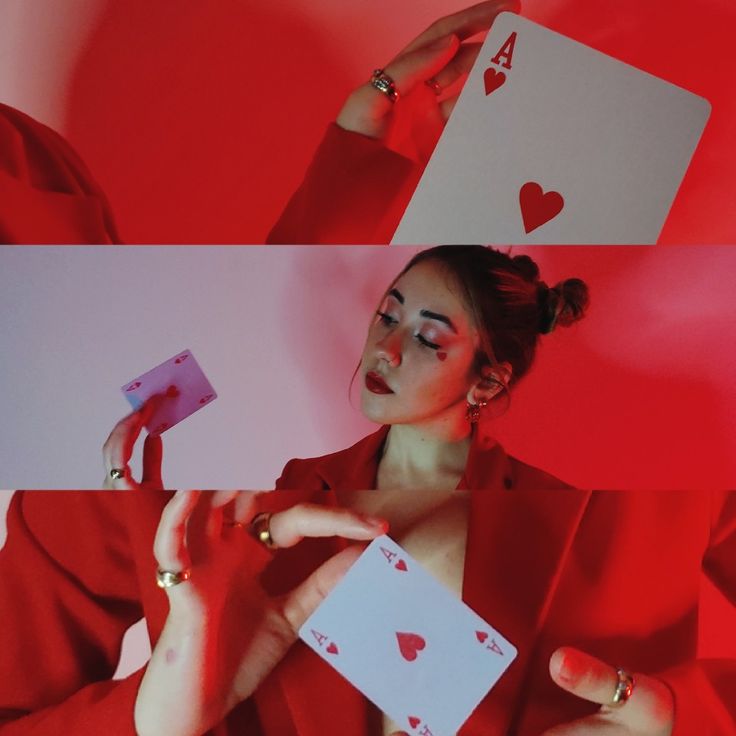 a woman in a red suit holding playing cards with hearts painted on her face and hands