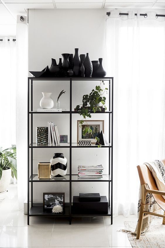 a black and white shelf with vases on it in front of a large window