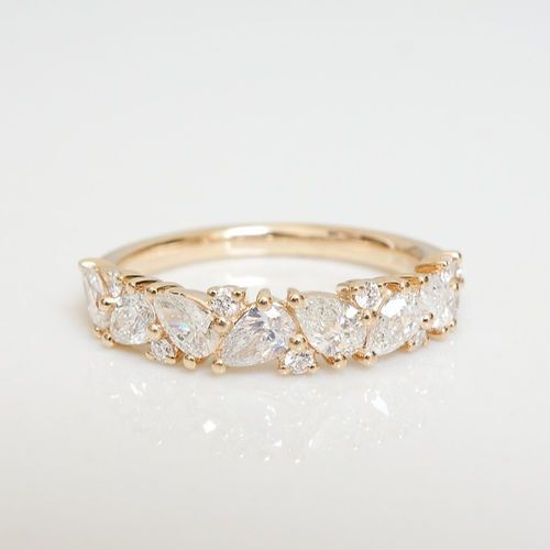 a yellow gold ring with five pear shaped diamonds on it's sides, set against a white background