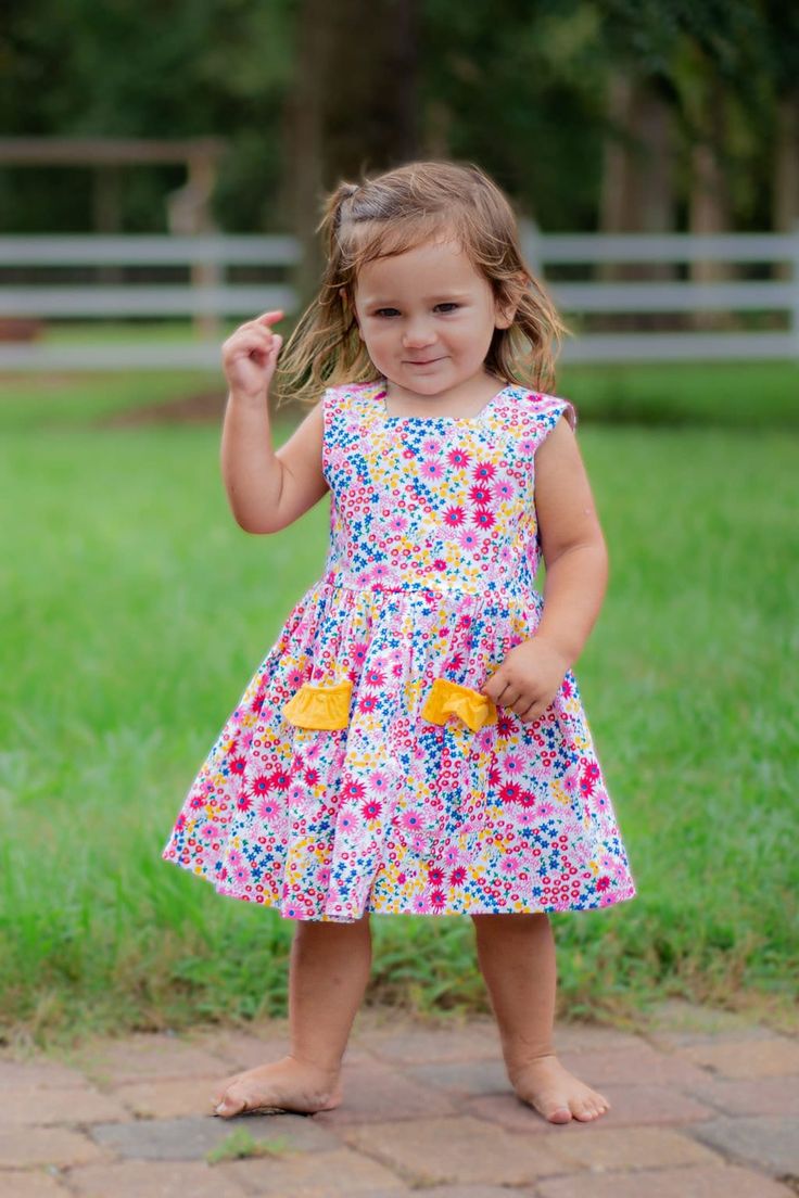 The Piper Dess is the perfect warm weather party frock with it bright floral fabric and yellow ruffle detail.  It is made of a 100% cotton and is fully lined.  Its fun flower buttons will delight your little one. Spring Cotton Sundress For Playdates, Spring Sundress For Playtime, Fun Multicolor Twirl Dress For Spring, Fun Spring Sundress For Playtime, Cute Multicolor Sundress For Garden Party, Summer Floral Print Dress For Playdate, Playful Spring Sundress For Playdate, Fun Cotton Dress For Garden Party, Fun Spring Twirl Dress For Playdate