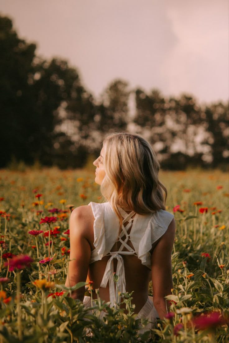 a woman sitting in a field of flowers