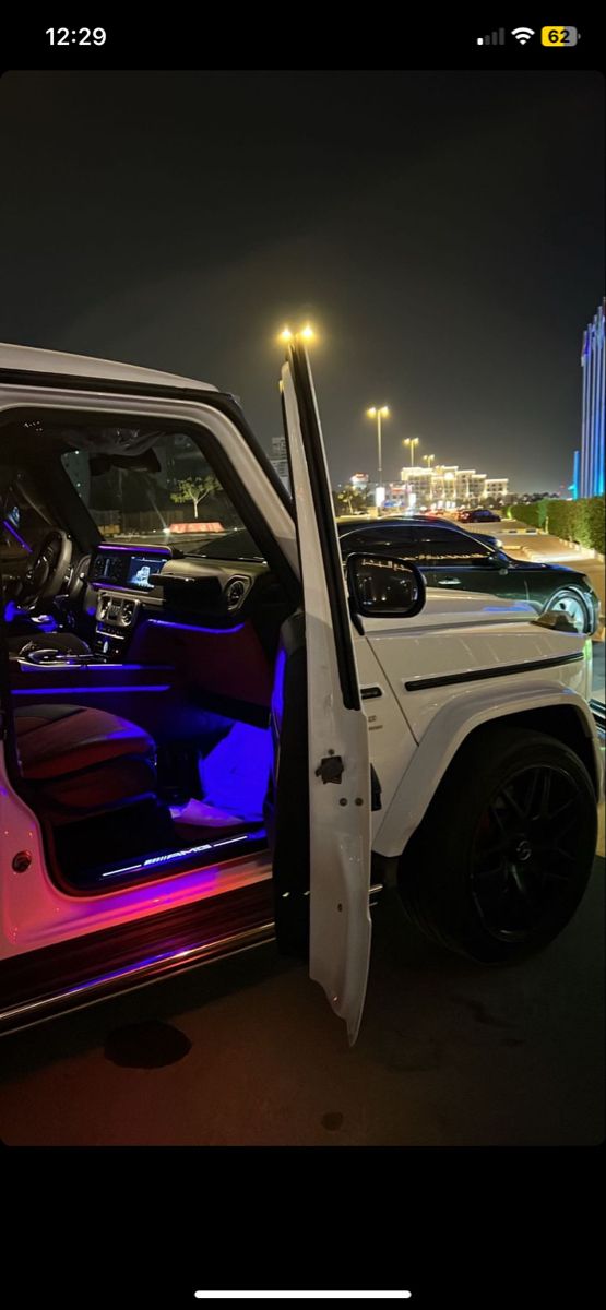 a white jeep with its door open and the interior lights on at night, parked in a parking lot