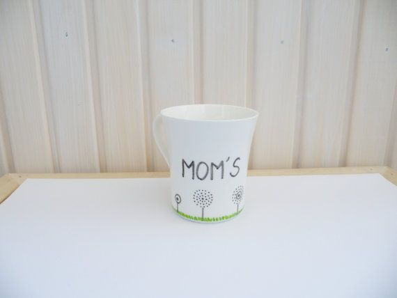 a cup with the word mom's written on it sitting on top of a table