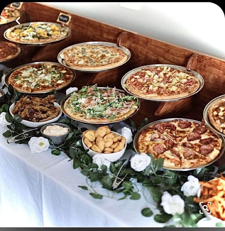 a table topped with lots of different types of pizzas and other foods on plates