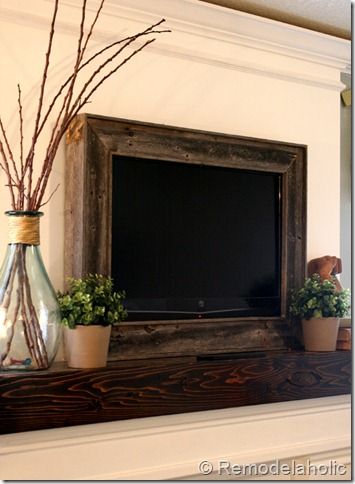 a tv sitting on top of a wooden mantle next to potted plants and vases