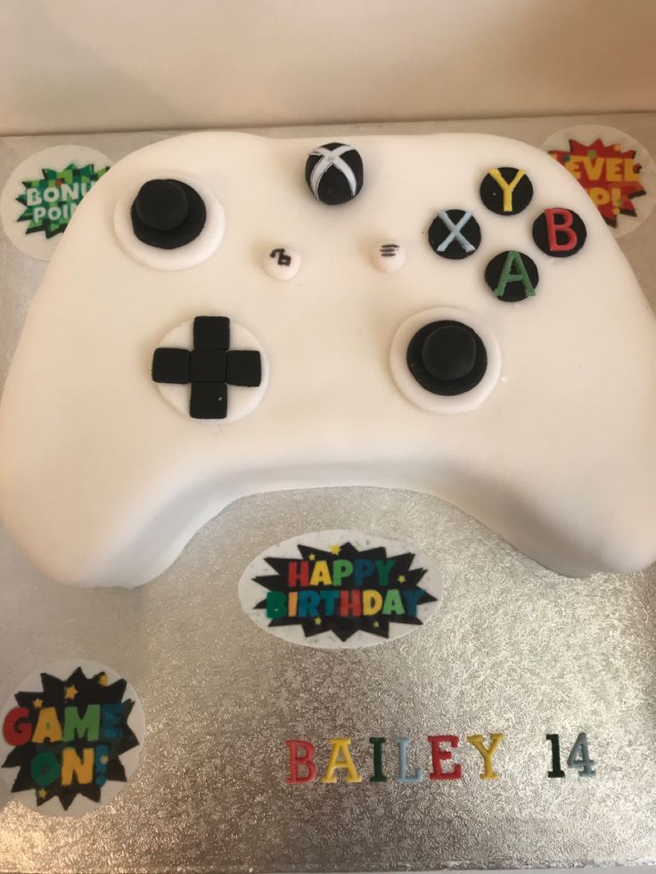 a cake shaped like a video game controller with happy birthday stickers on it's side