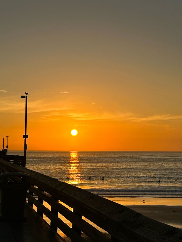 the sun is setting over the ocean and beach