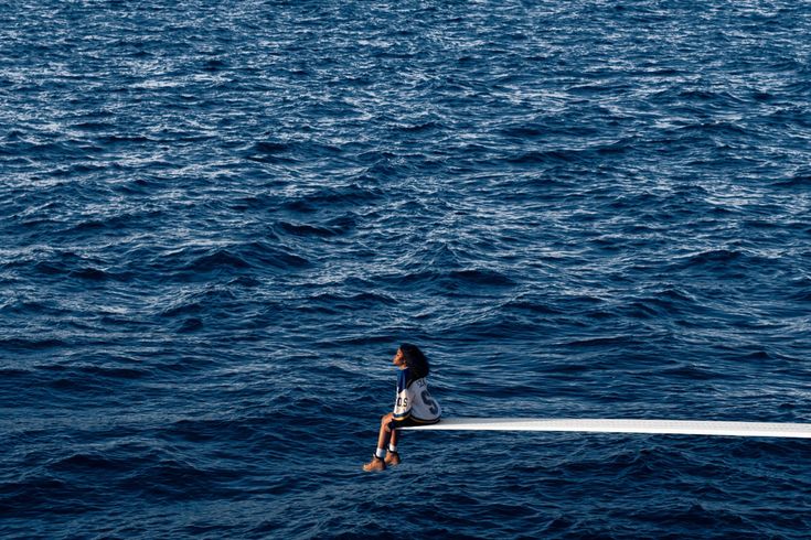 a woman sitting on top of a boat in the ocean