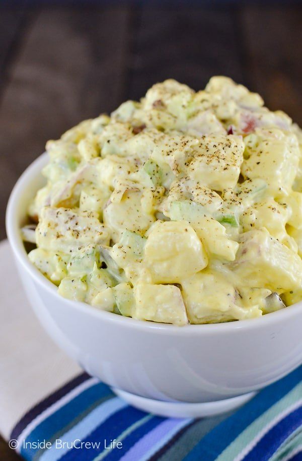 a white bowl filled with macaroni salad on top of a blue and white towel