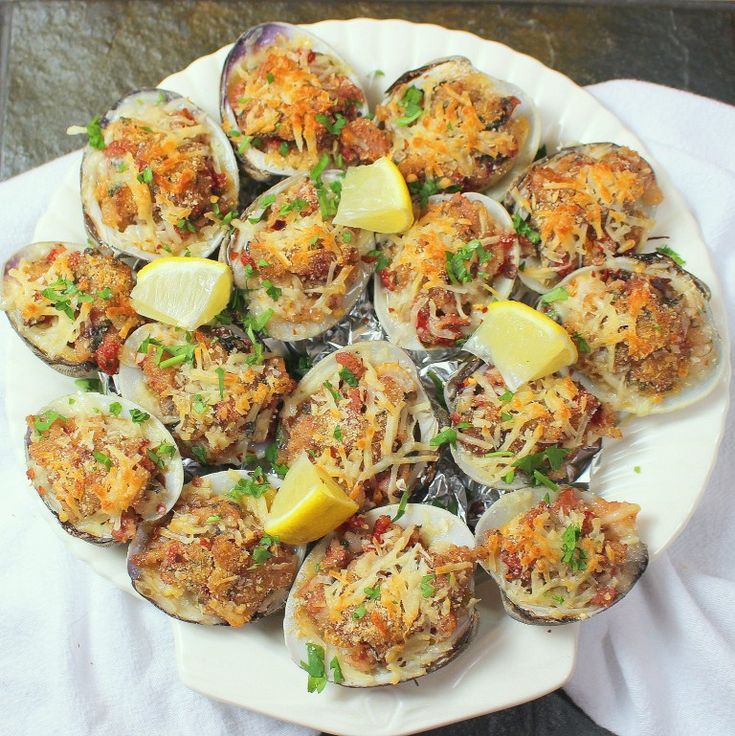 a white plate topped with cooked scallops and lemon wedges