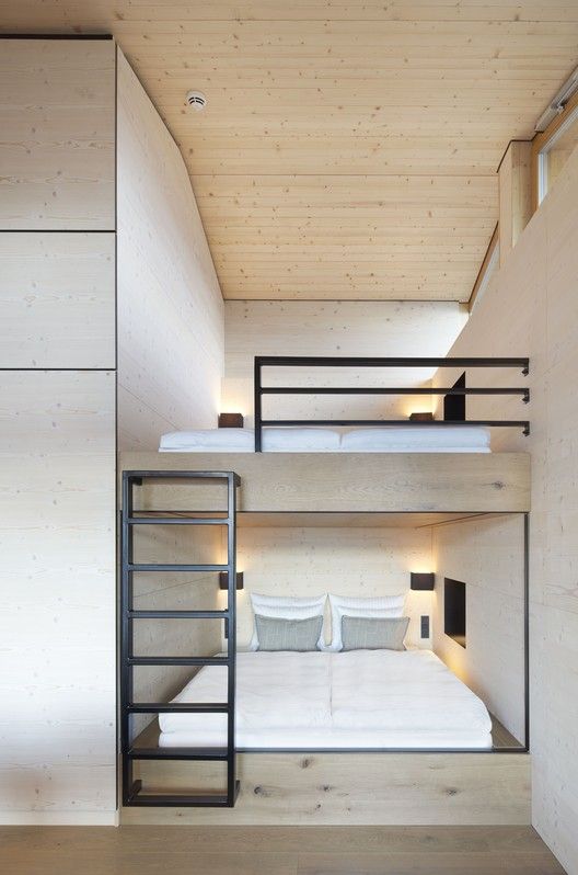 bunk beds are positioned in the middle of a room with wooden walls and flooring