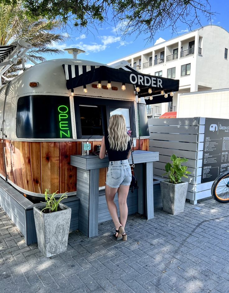 a woman is standing at the counter in front of an outdoor food truck that has been converted into a restaurant