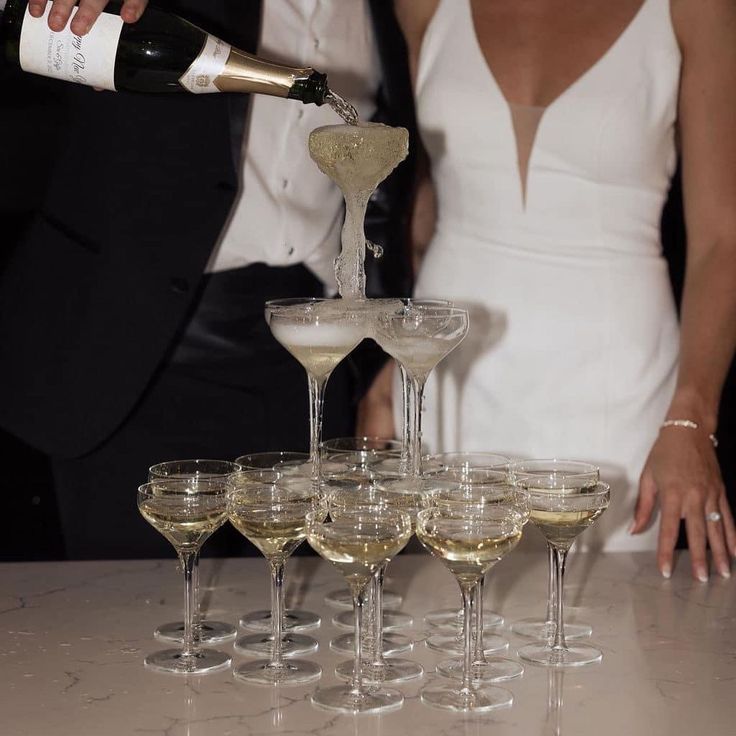 a bride and groom are pouring champagne into wine glasses for their wedding guests to drink