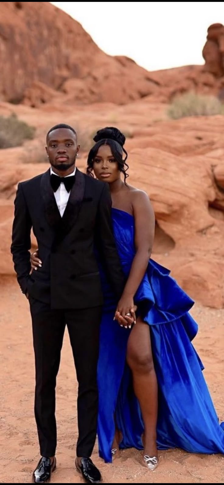 a man and woman in formal wear standing next to each other on a rocky surface