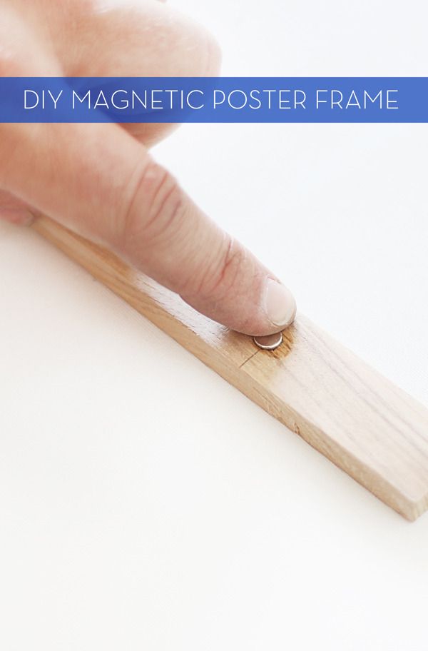 a person's finger on a wooden post with the text diy magnetic poster frame