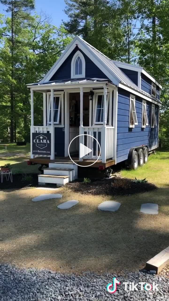 a tiny blue house sitting on top of a lush green field next to a forest