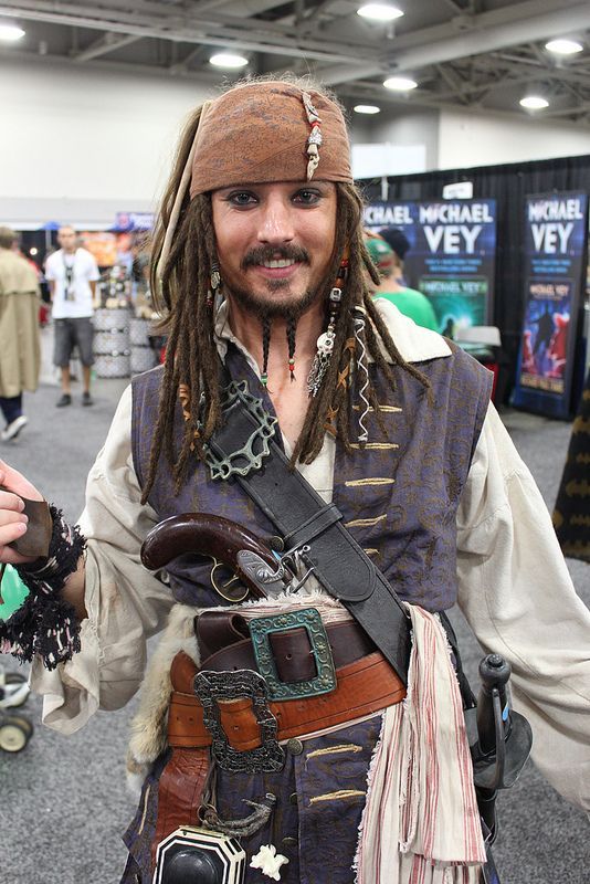 a man dressed up in pirate costume holding his hand out to the side while standing on a carpeted area