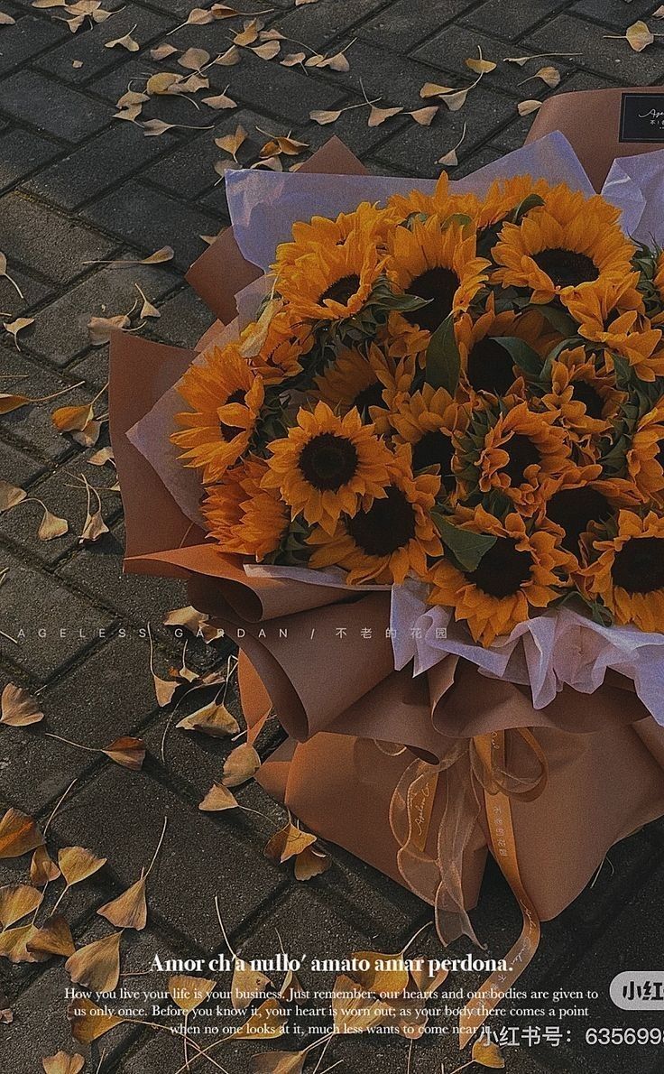 a bouquet of sunflowers is wrapped in brown paper and sitting on the ground