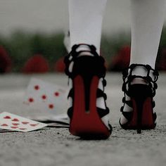 a woman's legs wearing high heeled shoes and playing cards on the ground