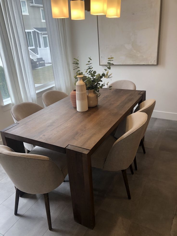 a dining room table with chairs and a vase on it