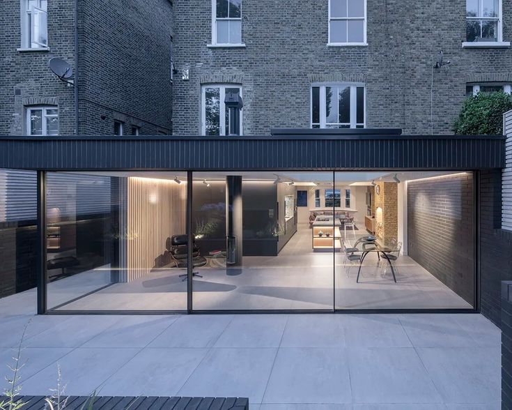 an open room with glass walls and sliding doors in front of a brick apartment building