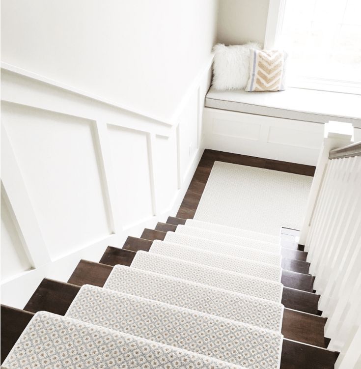 a set of stairs leading up to a window in a white room with wood flooring