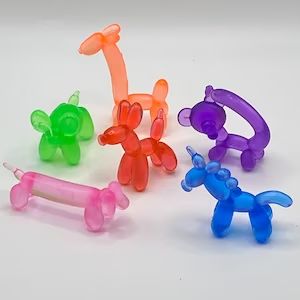 four different colored plastic dog toys on a white surface with one toy in the shape of a balloon