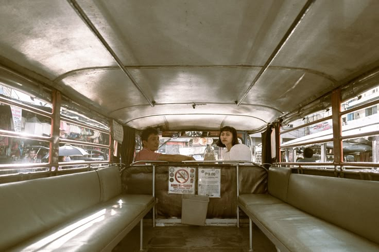 two people sitting in the back of a bus