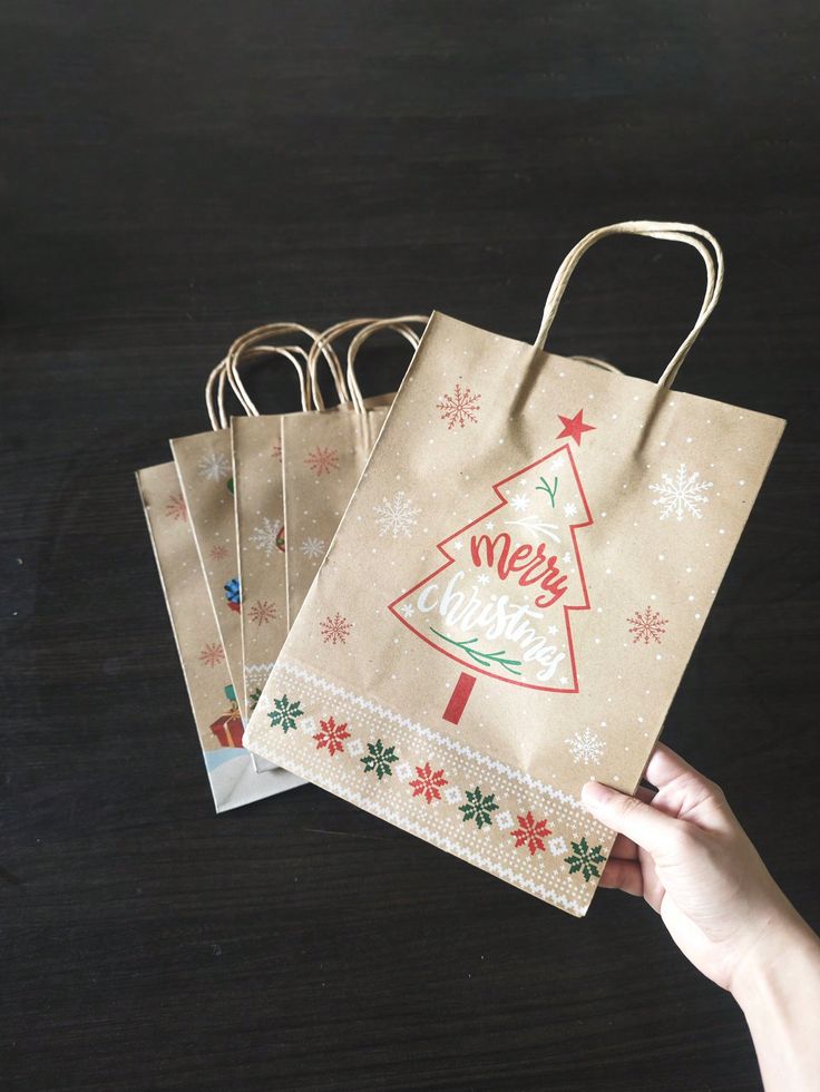 someone is holding three bags with christmas designs on them