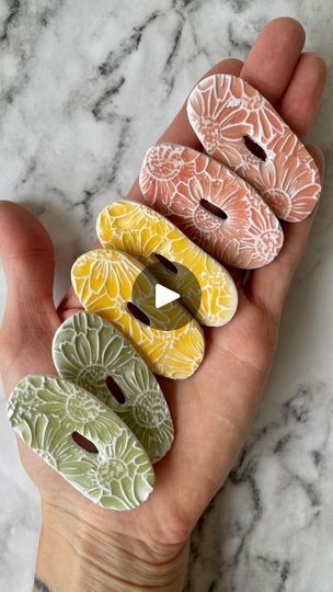 a person's hand holding five ceramic buttons