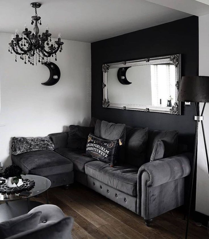 a black and white living room with couches, coffee table, chandelier and mirror