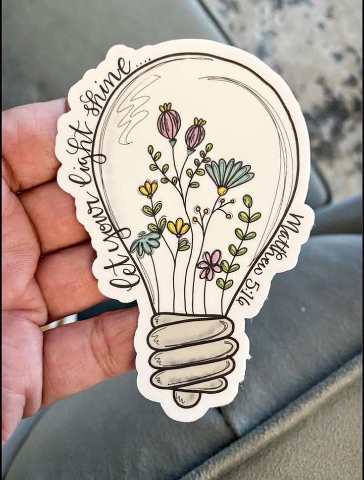 someone is holding up a sticker with flowers inside of an electric lightbulb