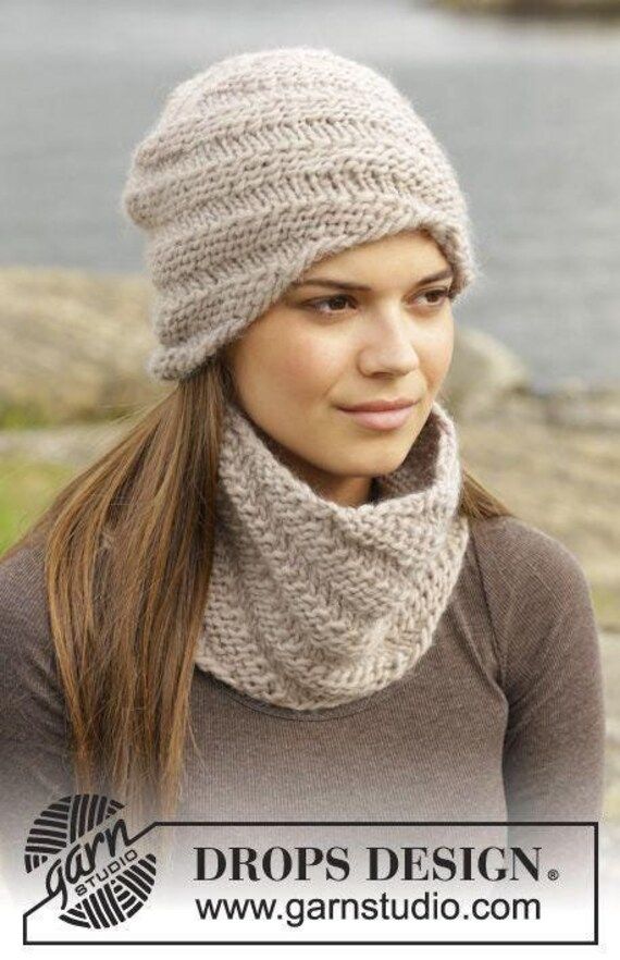 a woman wearing a knitted hat with a scarf around her neck and the words drops design on it