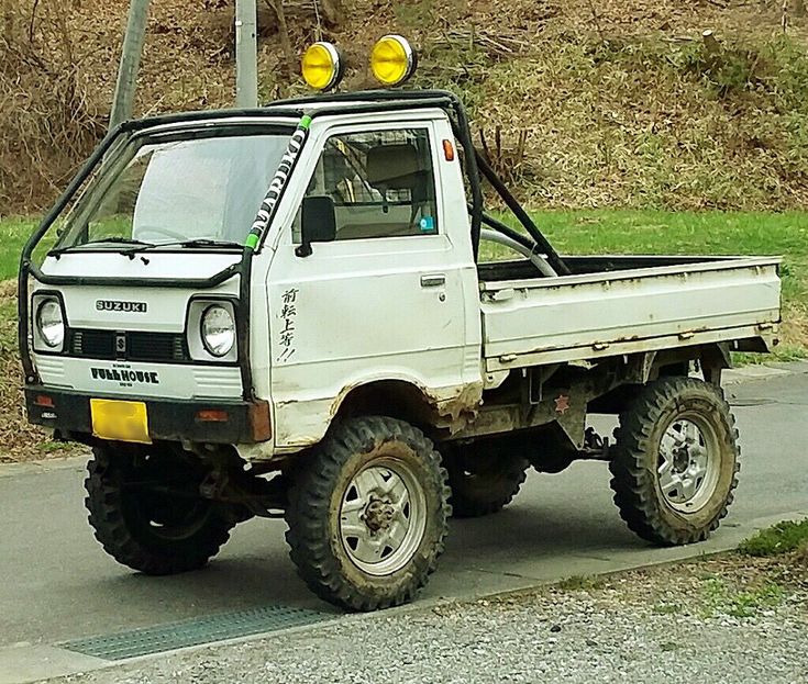 a white pick up truck parked on the side of a road next to a hill