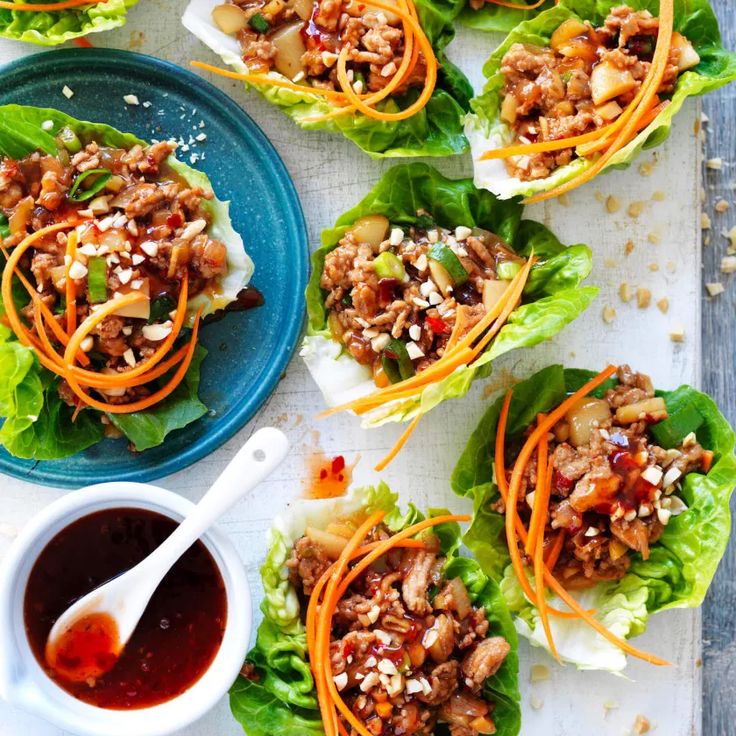 lettuce wraps with meat and carrots on a plate next to dipping sauce