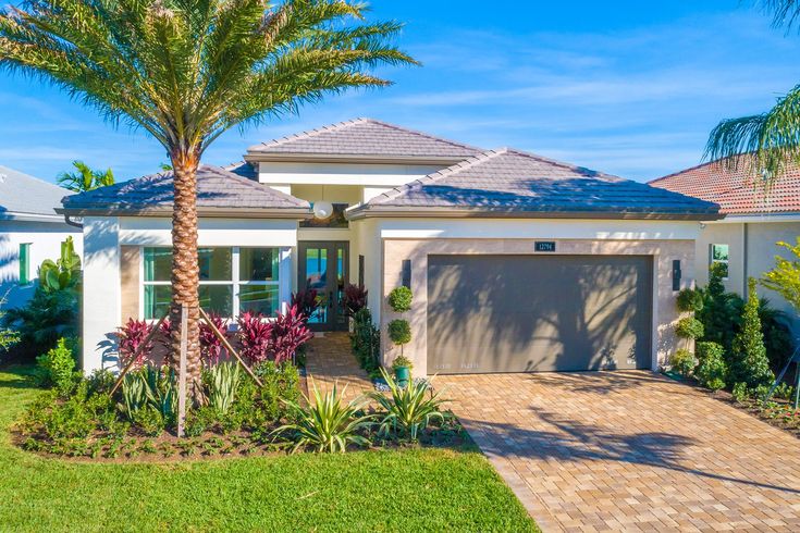 a home with palm trees and landscaping in front of the garage door is shown on a sunny day