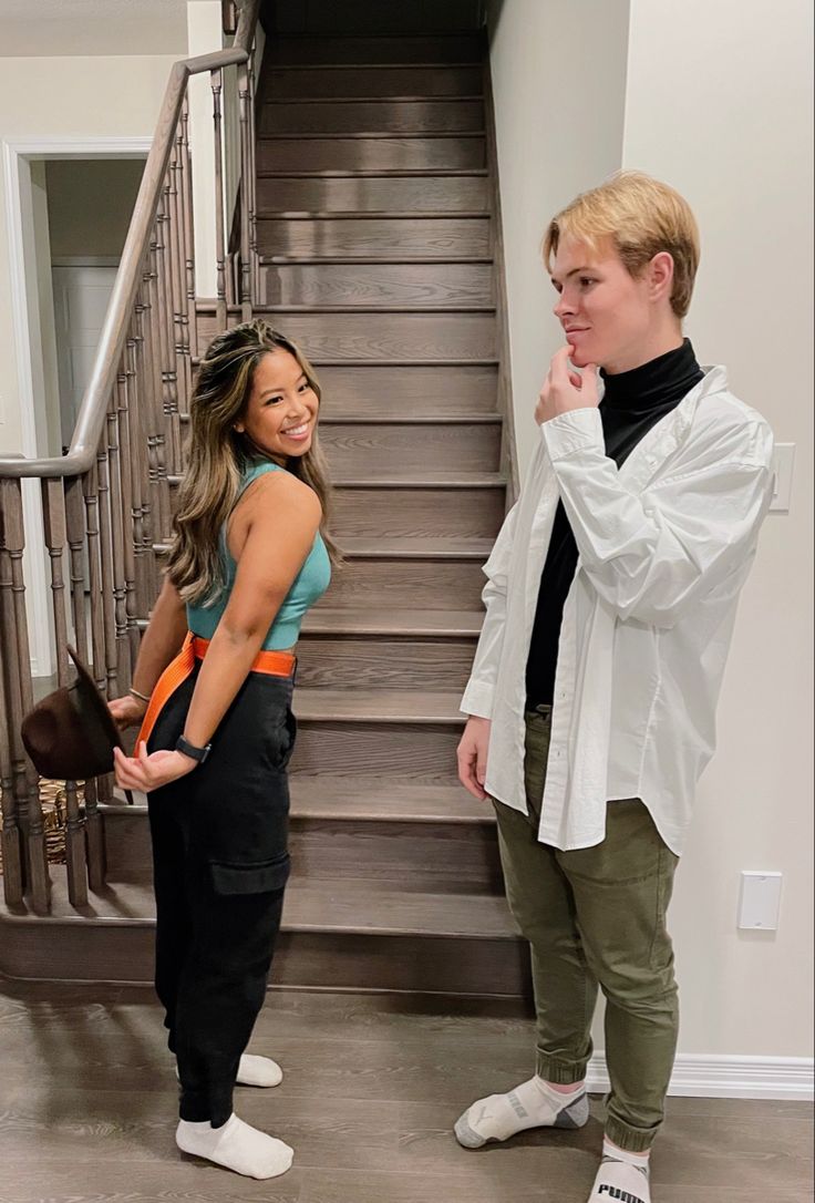 two people standing next to each other in front of stairs