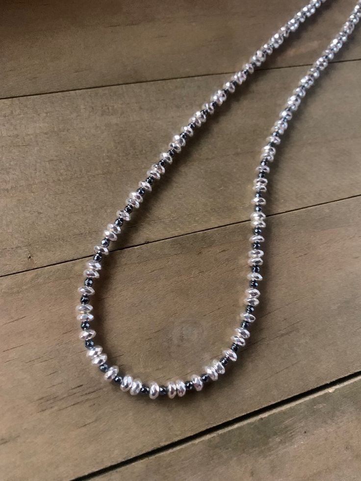 "This necklace is constructed with silver and dark gray hematite beads.  It has a repeating pattern and is strung on wire.  The necklace is finished with sterling silver findings including the crimps, hook clasp and extender chain.  The necklace is 17\" long (43.18 cm) and includes the sterling extender chain which will add another 2.25 inches/5.7 cm of length.  The silver faceted beads are hematite with a silver coating and are 4mm wide by 2mm tall.  The gray faceted beads are also hematite and Adjustable Beaded Necklaces With Sterling Silver Clasp, Silver Beaded Necklace With Oval Beads, Adjustable Silver Necklace With Black Beads, Silver Jewelry With Single Strand Oval Beads, Adjustable Silver Beaded Necklace With Sterling Clasp, Silver Beaded Necklace With Spacer And Oval Beads, Sterling Silver Beaded Necklaces With Black Beads, Silver Adjustable Beaded Necklace With Polished Beads, Silver Beaded Necklace With Sterling Silver Clasp