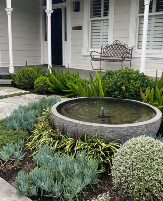 a water fountain in front of a white house