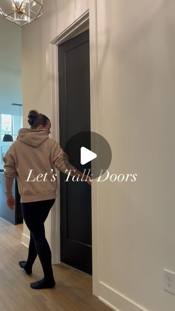 a woman in black pants and a tan hoodie is opening the door to her apartment